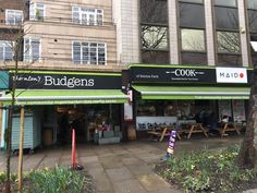 the outside of a restaurant with green awnings and trees in front of it