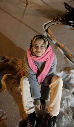 a woman sitting on top of a snow covered ground