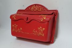 a red box with gold designs on the front and sides sitting on a white surface