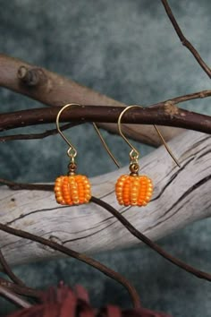 small orange beaded pumpkin earrings on a branch