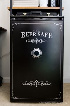 the beer safe cabinet is black with white lettering on it and an ornate border around the door