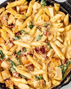 a skillet filled with pasta, chicken and spinach