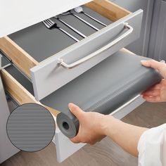 a person is opening the drawer to place utensils on top of the drawers