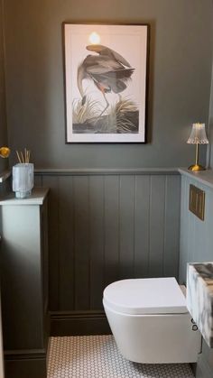 a white toilet sitting in a bathroom next to a painting on the wall above it