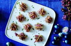 small appetizers are arranged on a platter next to christmas ornaments and berries