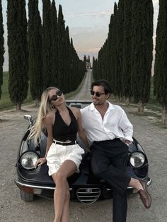 a man and woman sitting on top of a car