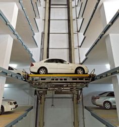 a white car is parked on top of a conveyor belt in a parking garage