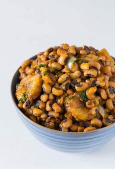 a blue bowl filled with beans and other food on top of a white tablecloth