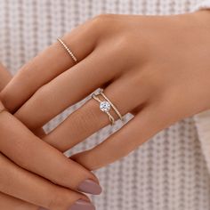 a woman's hand with two rings on her fingers and the ring has a diamond in it