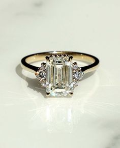 an emerald cut diamond ring on a white surface