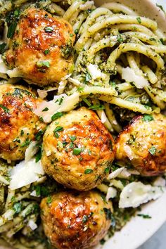 a white plate topped with pasta and meatballs covered in parmesan cheese sauce