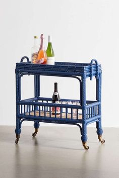 a blue wicker bar cart with bottles on it