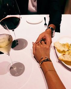 two people are sitting at a table with wine glasses and food in front of them