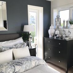 a bedroom with blue walls and white bedding, mirrors on the wall and dresser