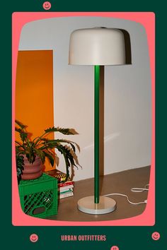 a green and white lamp sitting on top of a wooden table next to a potted plant