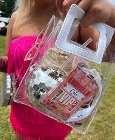 a woman in a pink dress is holding a clear bag with various items inside it