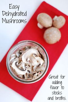 a jar filled with mushrooms sitting on top of a red place mat next to two cloves