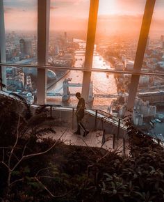 a man standing on top of a tall building looking out at the city from below