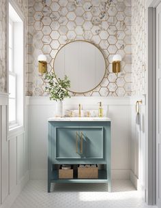 a bathroom with a blue vanity and gold accents on the wall, along with a round mirror