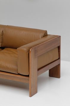 a brown leather couch sitting on top of a white floor next to a wooden frame