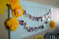 a blue door with yellow flowers hanging from it's side and pictures on the wall