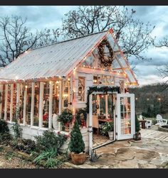 a small white house with christmas lights on it's roof and windows in the front