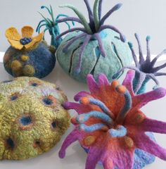 four different types of felt flowers on a white surface