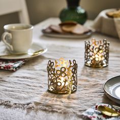 candles are sitting on a table with plates and cups