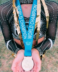 a woman holding a medal in her hands with the words world champion written on it