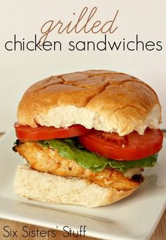 a chicken sandwich with tomatoes and lettuce on a white plate