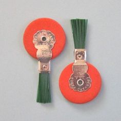 two orange buttons with green tassels on them