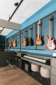 guitars are lined up on the wall in this music studio room with blue walls and black cabinets