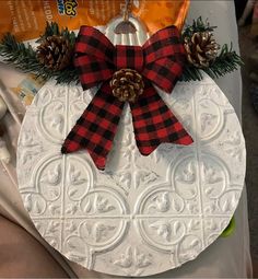 a christmas ornament with pine cones and plaid bow on it's front