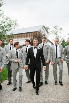 a group of men in suits walking down a dirt road