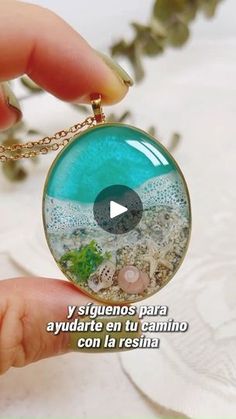 a person is holding a necklace with an image of the ocean in it and text that reads