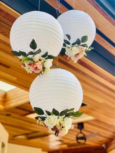 three white paper lanterns with flowers hanging from them