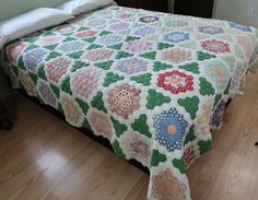 a bed with a quilt on top of it in a bedroom next to a nightstand