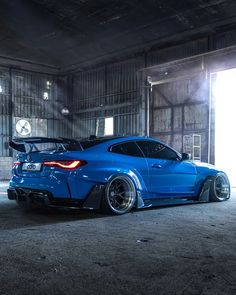 the blue sports car is parked in an empty garage with its hood up and tail lights on