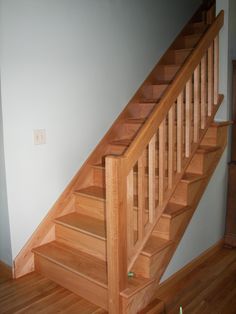 a wooden stair case next to a white wall