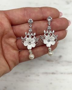 a pair of white flowers and pearls are on the finger of a woman's hand