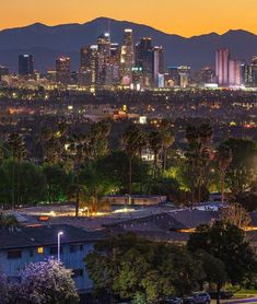 the city skyline is lit up at night, with mountains in the backgroud