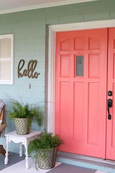 a pink door with two planters on the porch