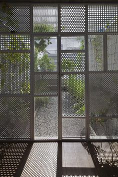 an open window with metal mesh covering it and some trees in the back ground below