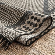 a black and white rug with fringes laying on top of the floor next to it