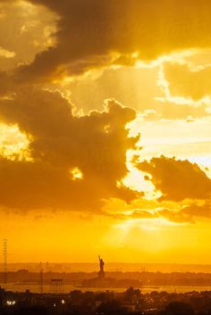 the sun is setting over an island with a statue in the distance by luma photography for stockstation