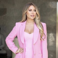 a woman in a pink suit posing for the camera with her hands on her hips