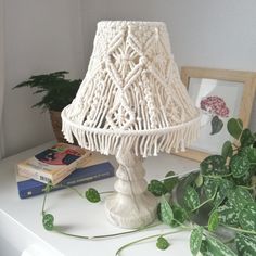 a white lamp sitting on top of a table next to a potted green plant