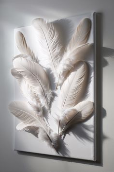 white feathers are arranged on the wall in an art work that is made out of acrylic paint