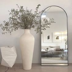 a large white vase sitting next to a mirror