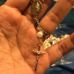 a hand holding a rosary and a cross with a coin hanging from it's middle finger